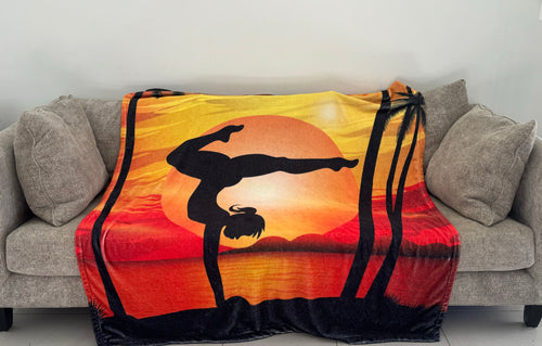 A fleece blanket with a gymnast silhouette performing a handstand on a sunset background.