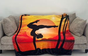 A fleece blanket with a gymnast silhouette performing a handstand on a sunset background.